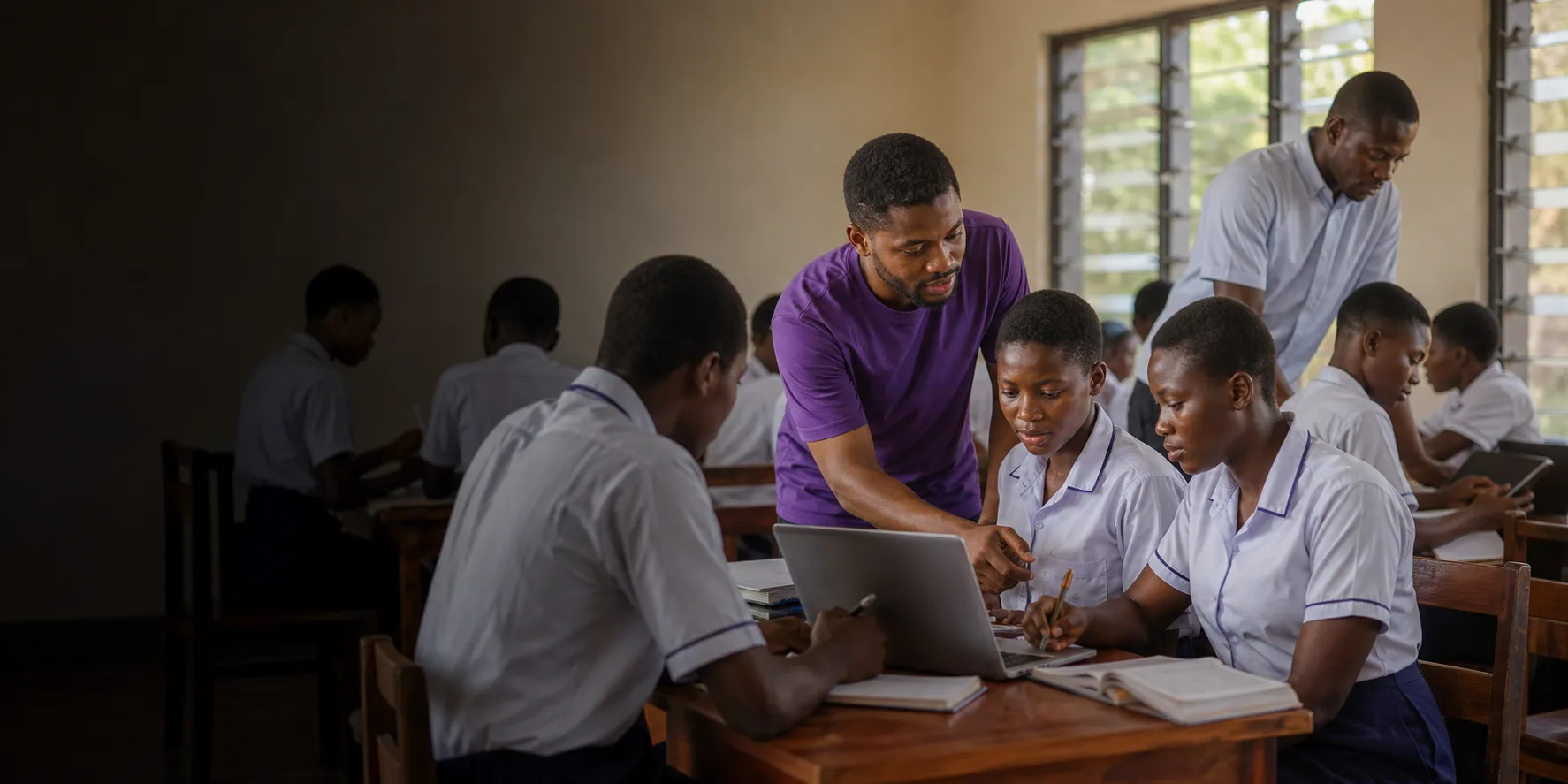 Students using improved learning resources with support from a teacher and alumnus